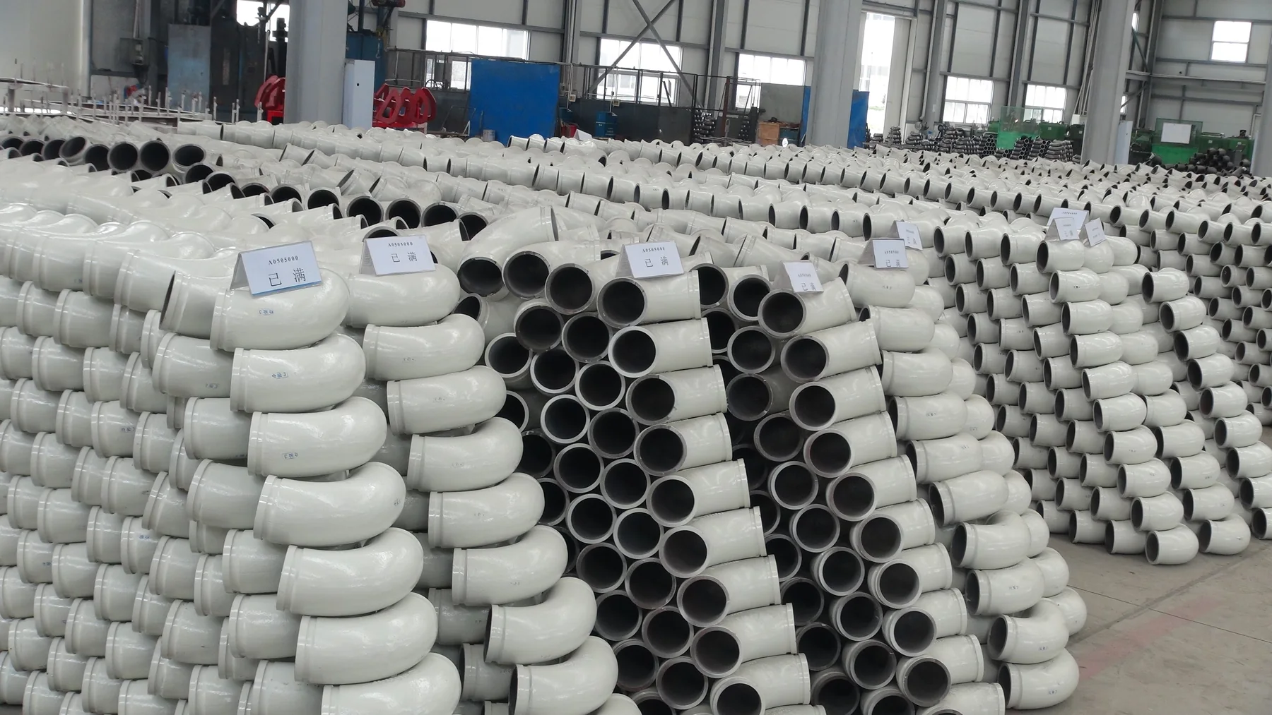 生产现场批量码放的贝钢耐磨弯管和直管